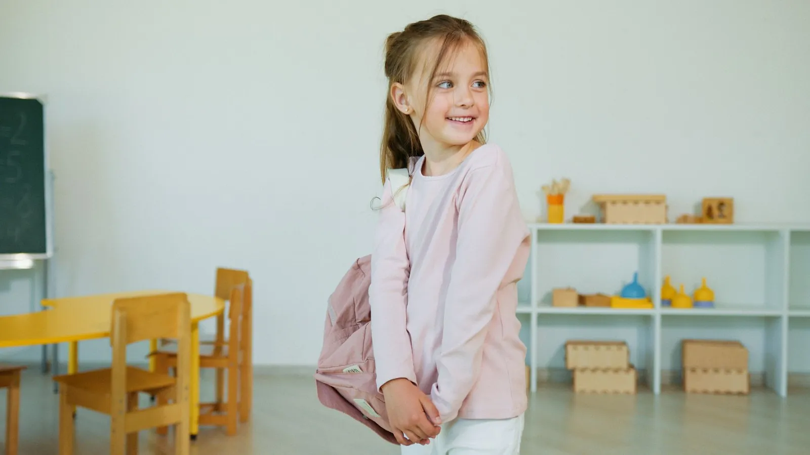 A smiling schoolgirl with her backpack in a classroom