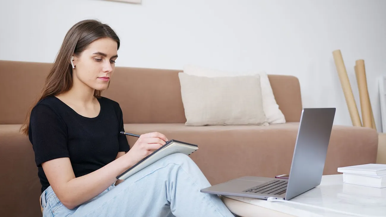 A woman studying the online IEP advocate course at home, taking notes by her laptop